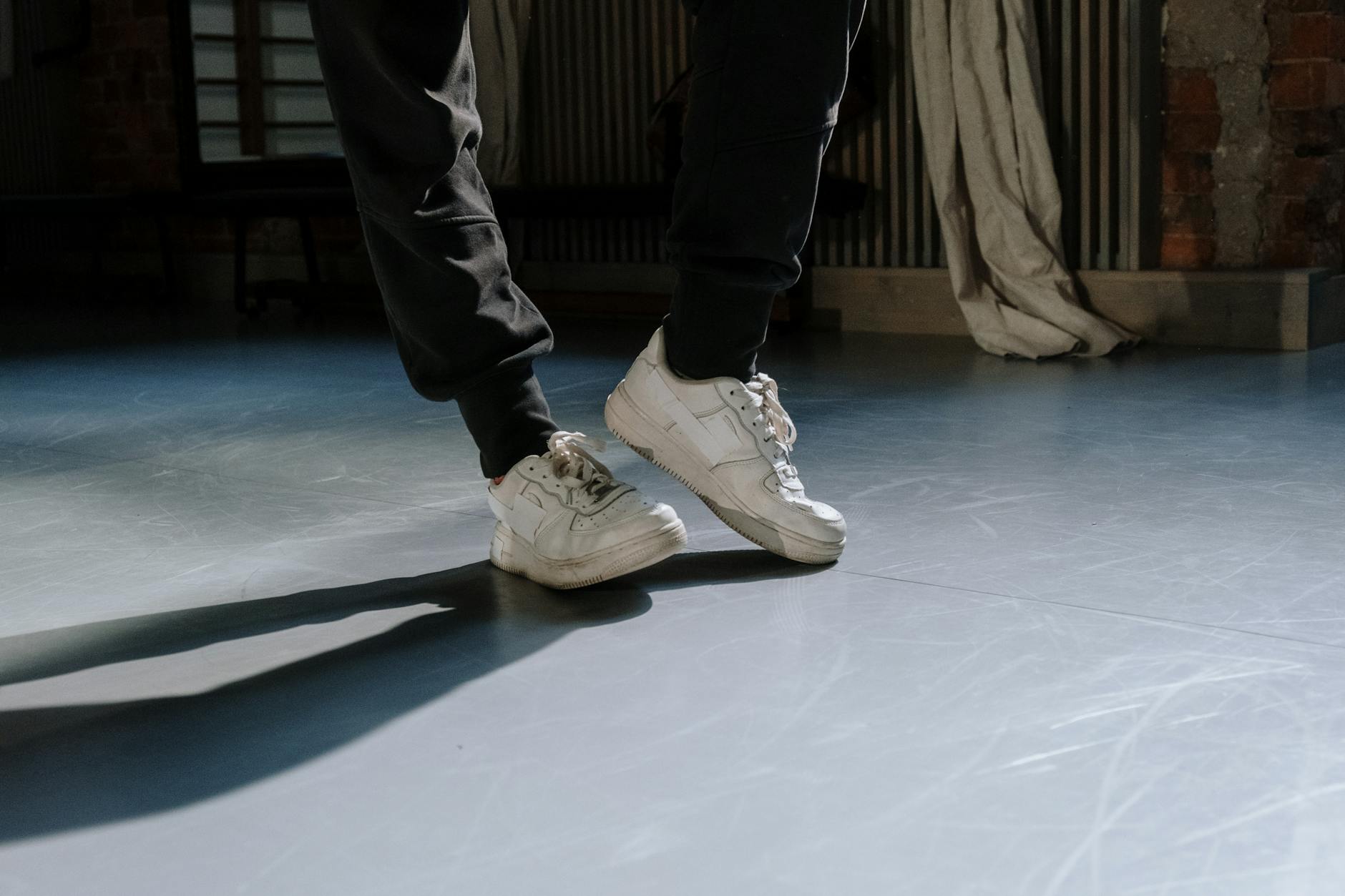 Białe sneakersy w ruchu na gładkiej podłodze, gotowe do nocnego tańca