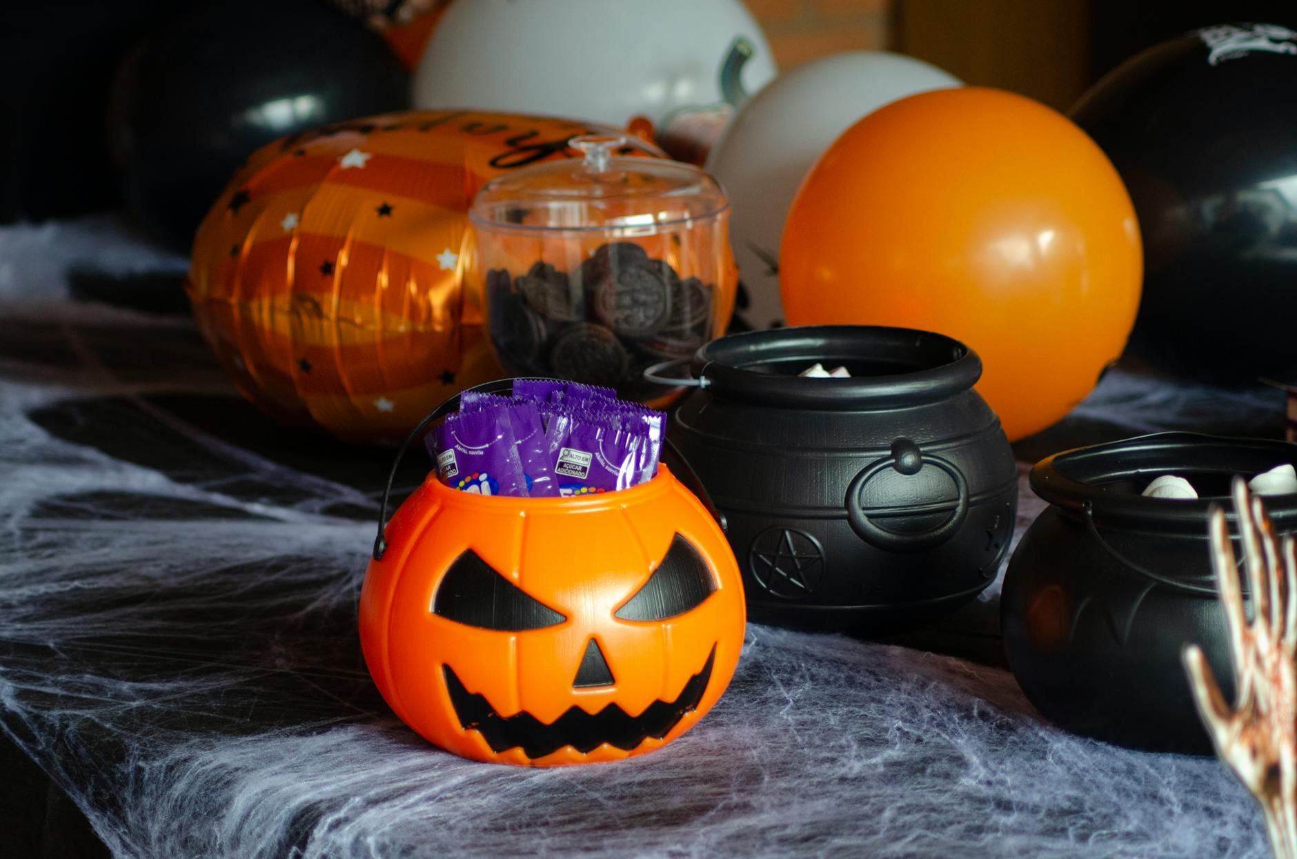 Stół z halloweenowymi słodyczami, dyniowym wiadrem i kociołkami