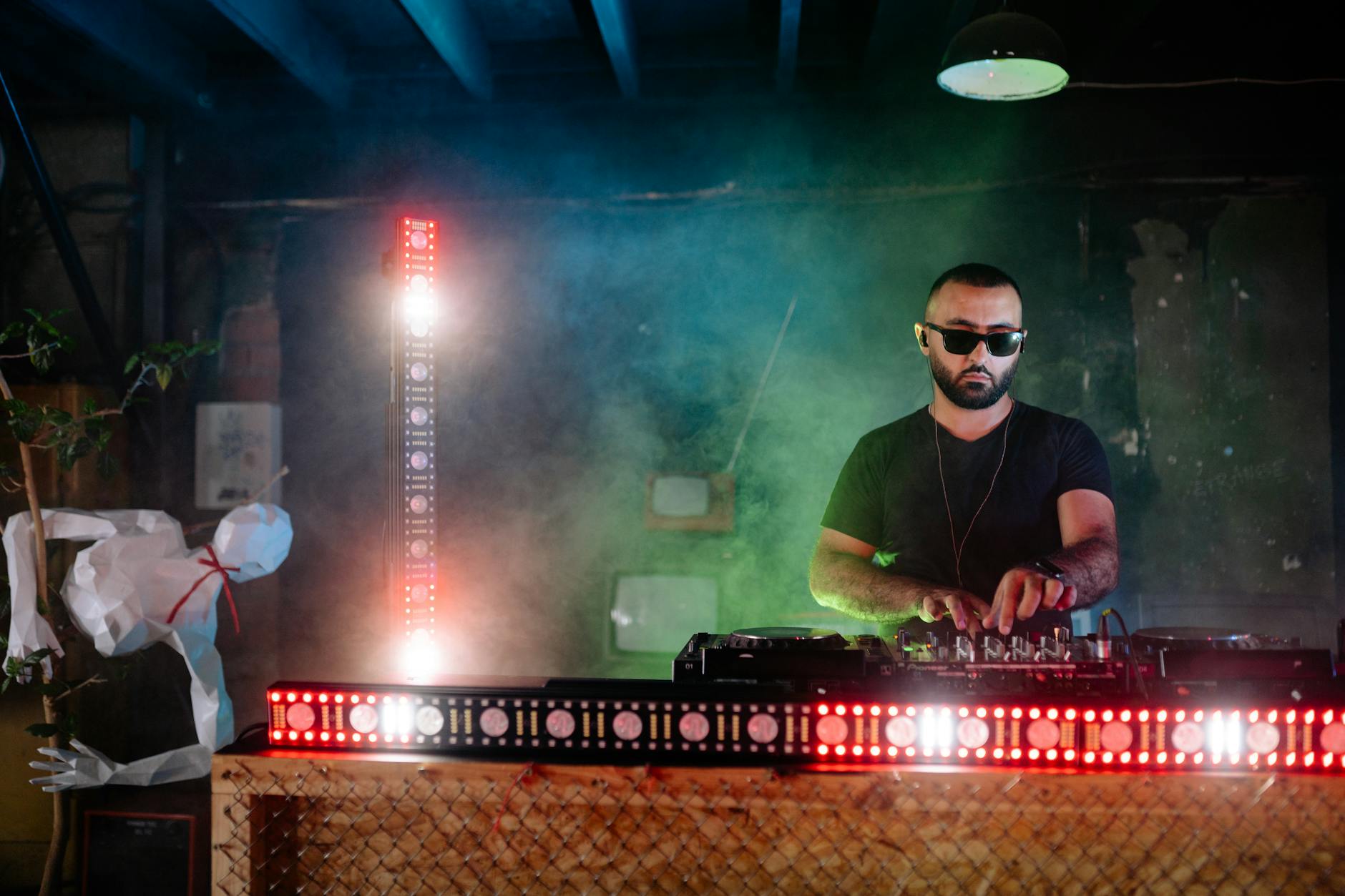 DJ przy konsolecie w klubie z kolorowymi światłami i dymem