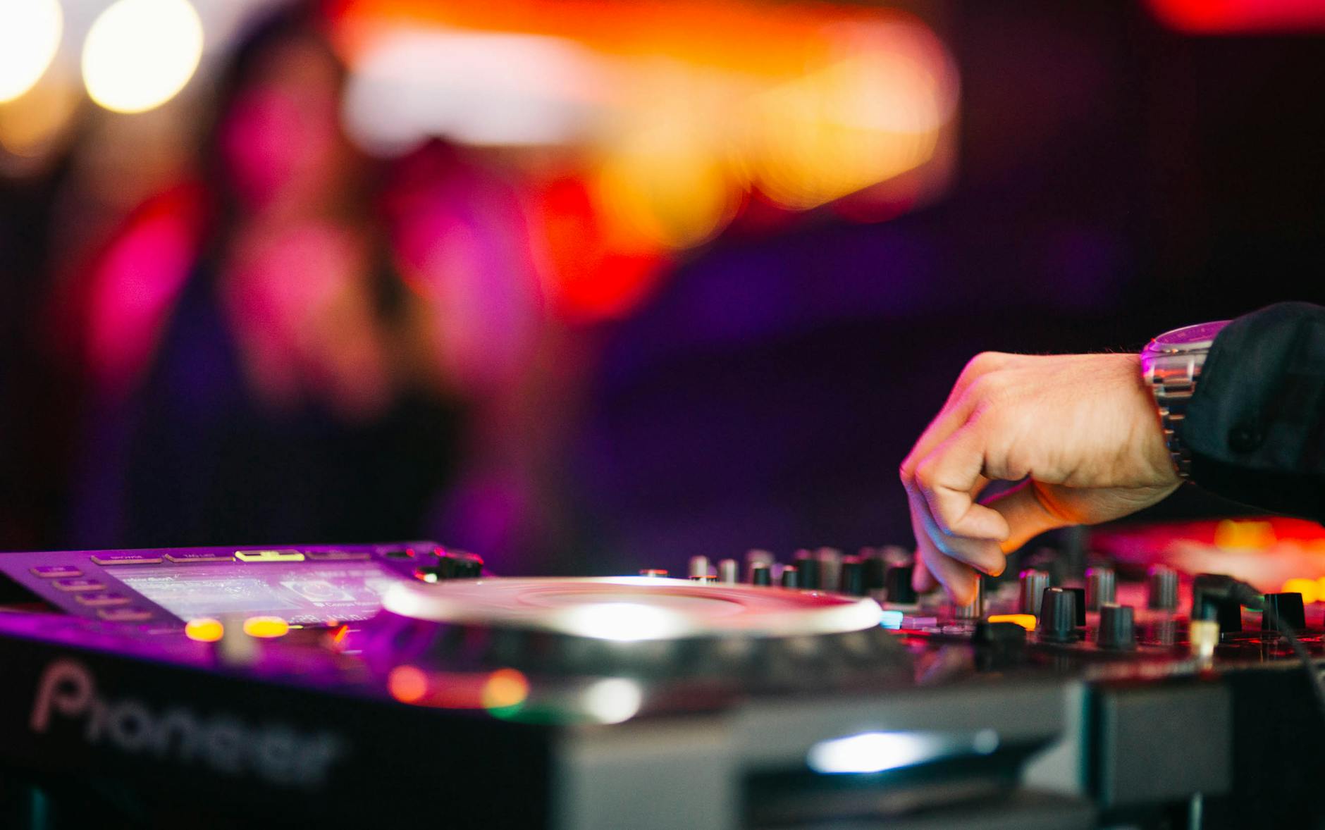 Dłoń DJ-a miksująca muzykę na gramofonie w zatłoczonym klubie
