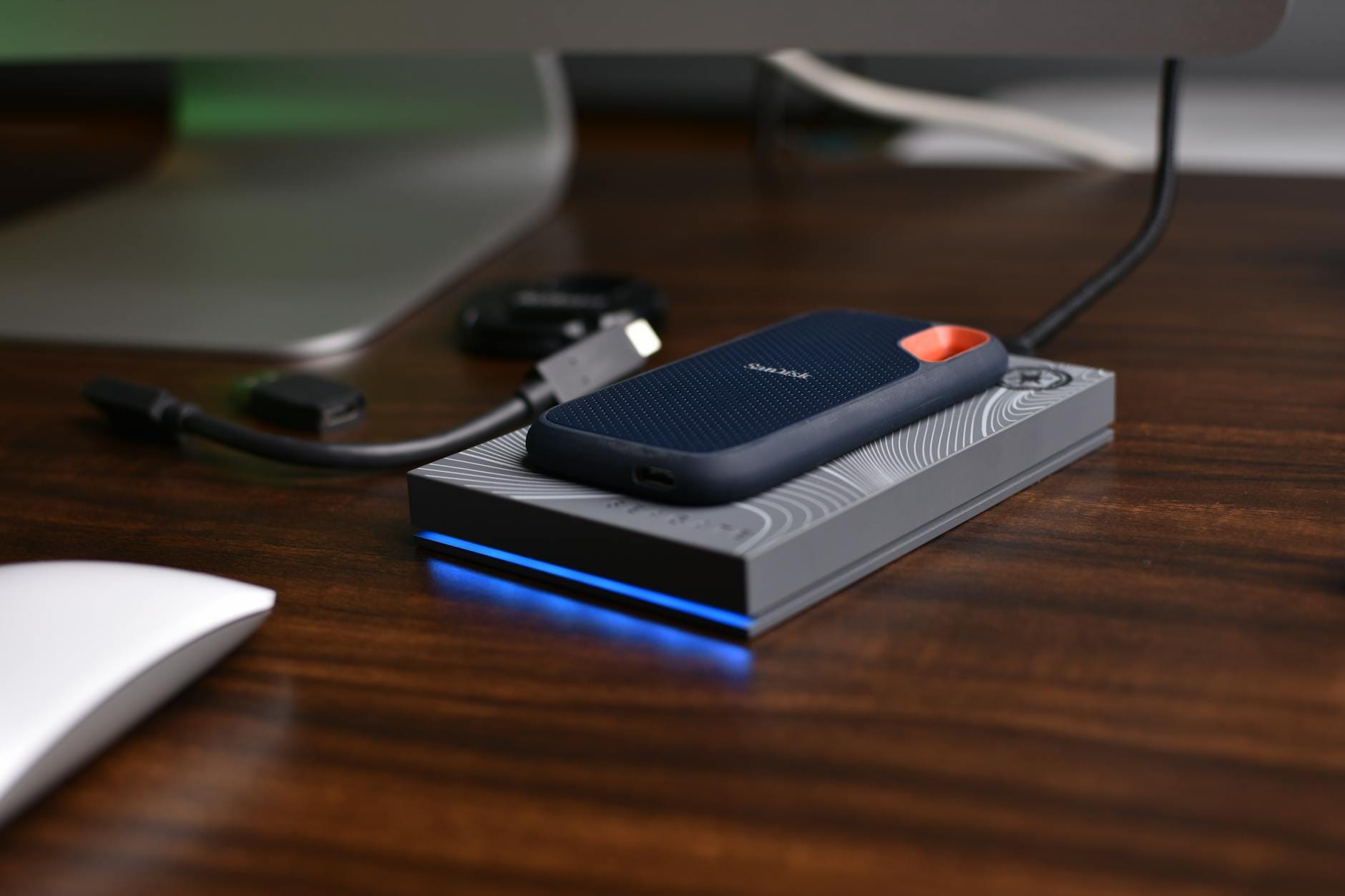 Przenośny dysk SSD USB z podłączonymi kablami na drewnianym biurku