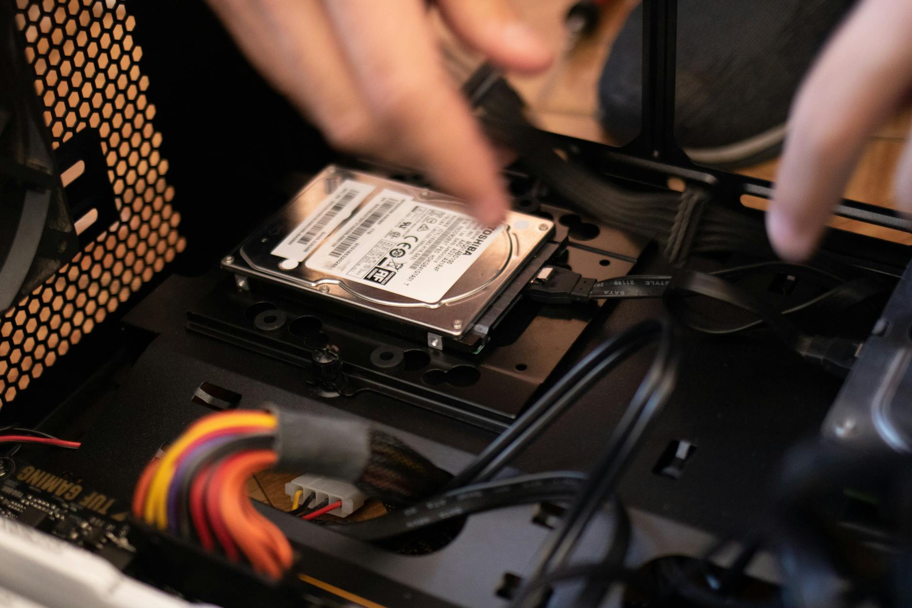 Ręce montujące dysk SSD w obudowie komputera