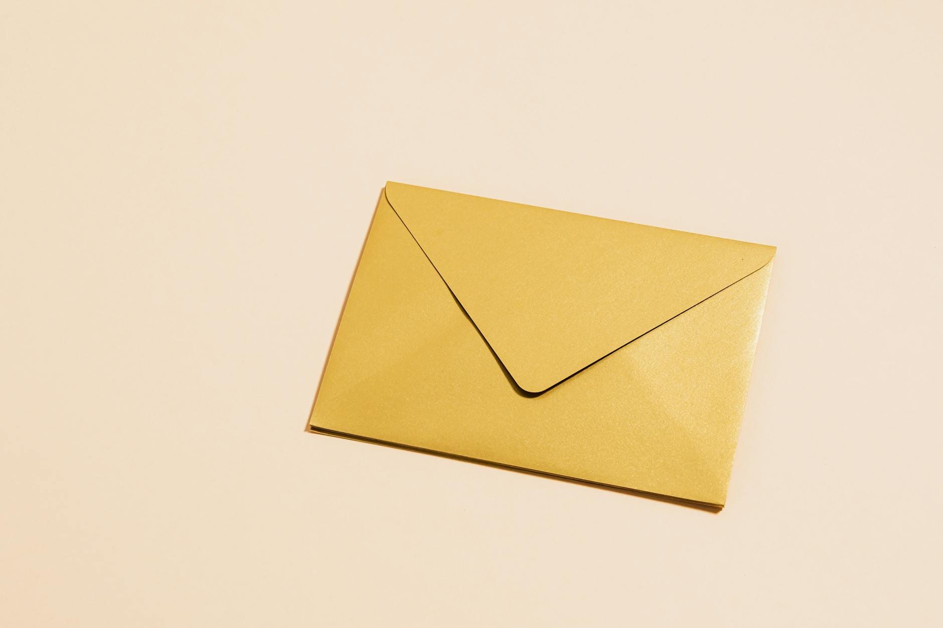 Złota koperta ślubna na żółtym tle