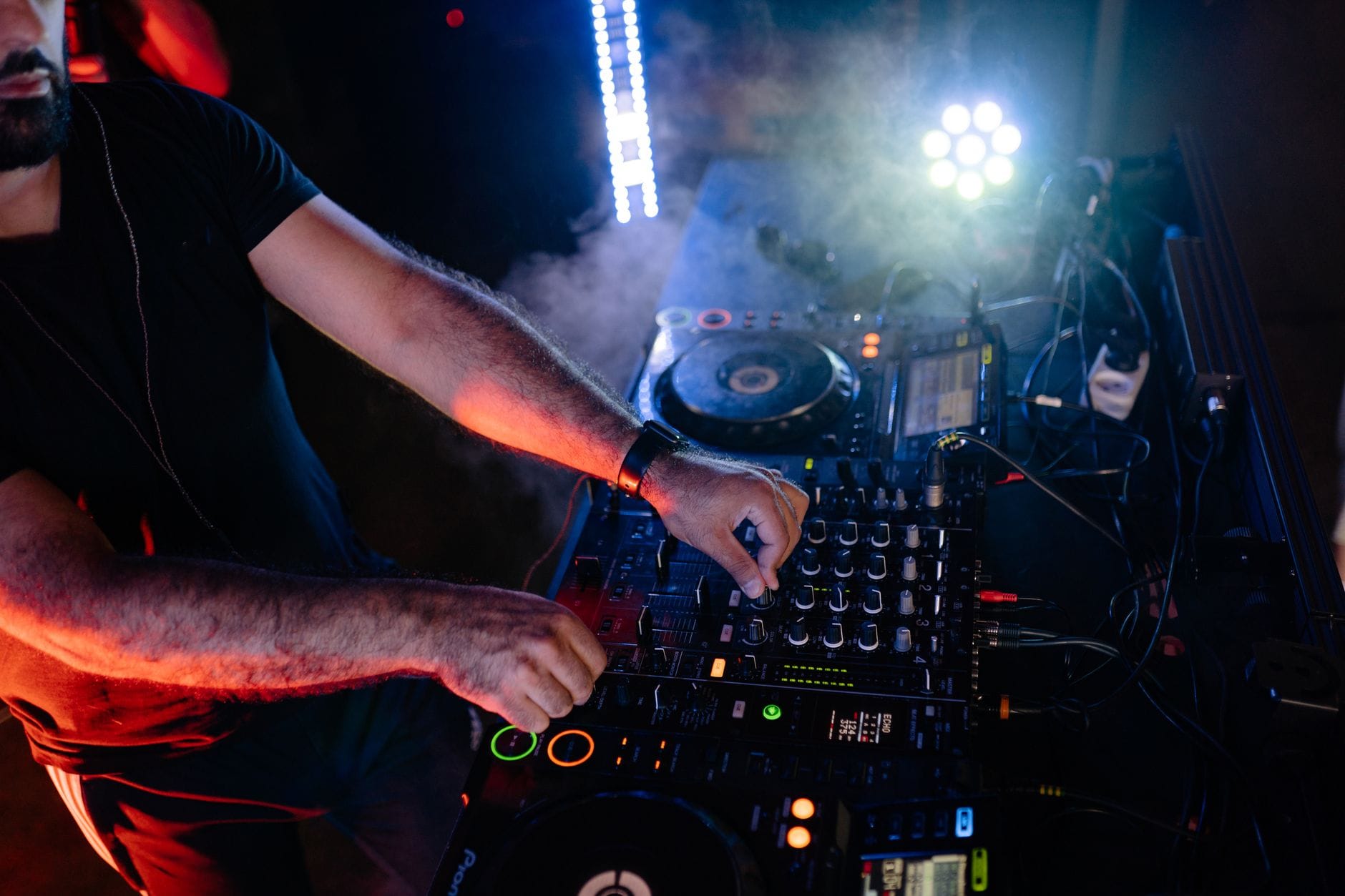 DJ miksuje utwory przy kolorowych światłach w klubie nocnym