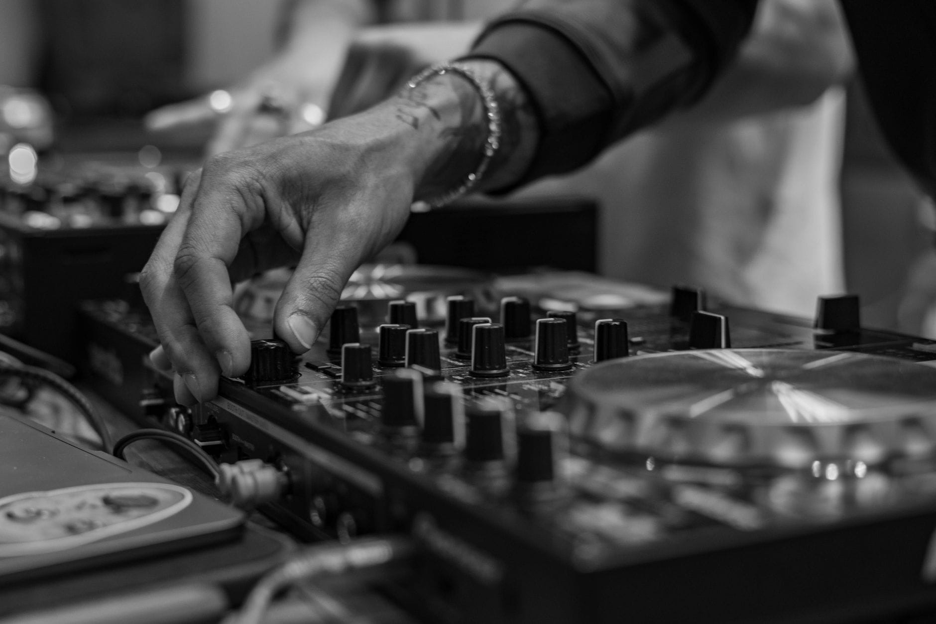 Dłoń DJ-a regulująca pokrętła miksera w czarno-białym ujęciu