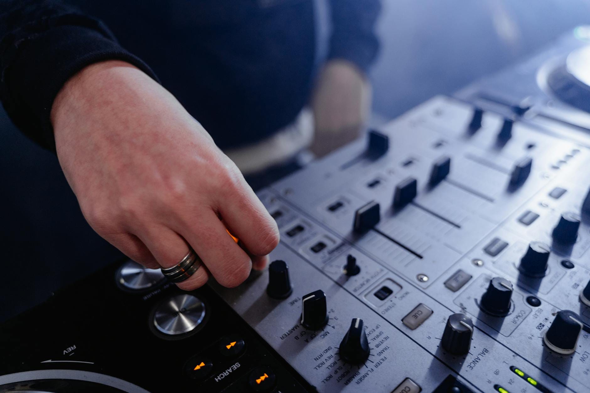 Dłoń regulująca pokrętła na mikserze DJ podczas imprezy w klubie