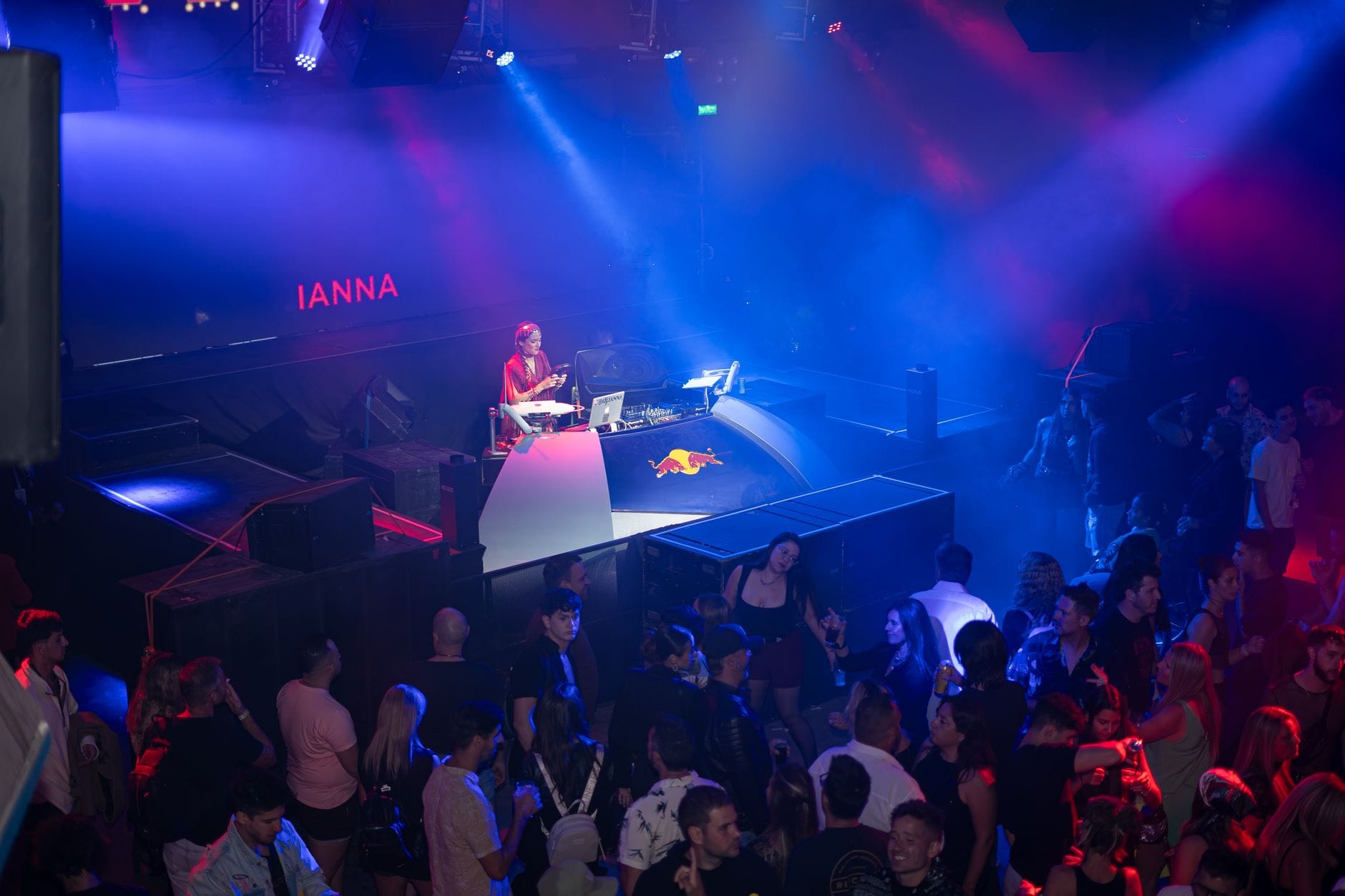 DJ gra w klubie nocnym przy kolorowych światłach i tłumie