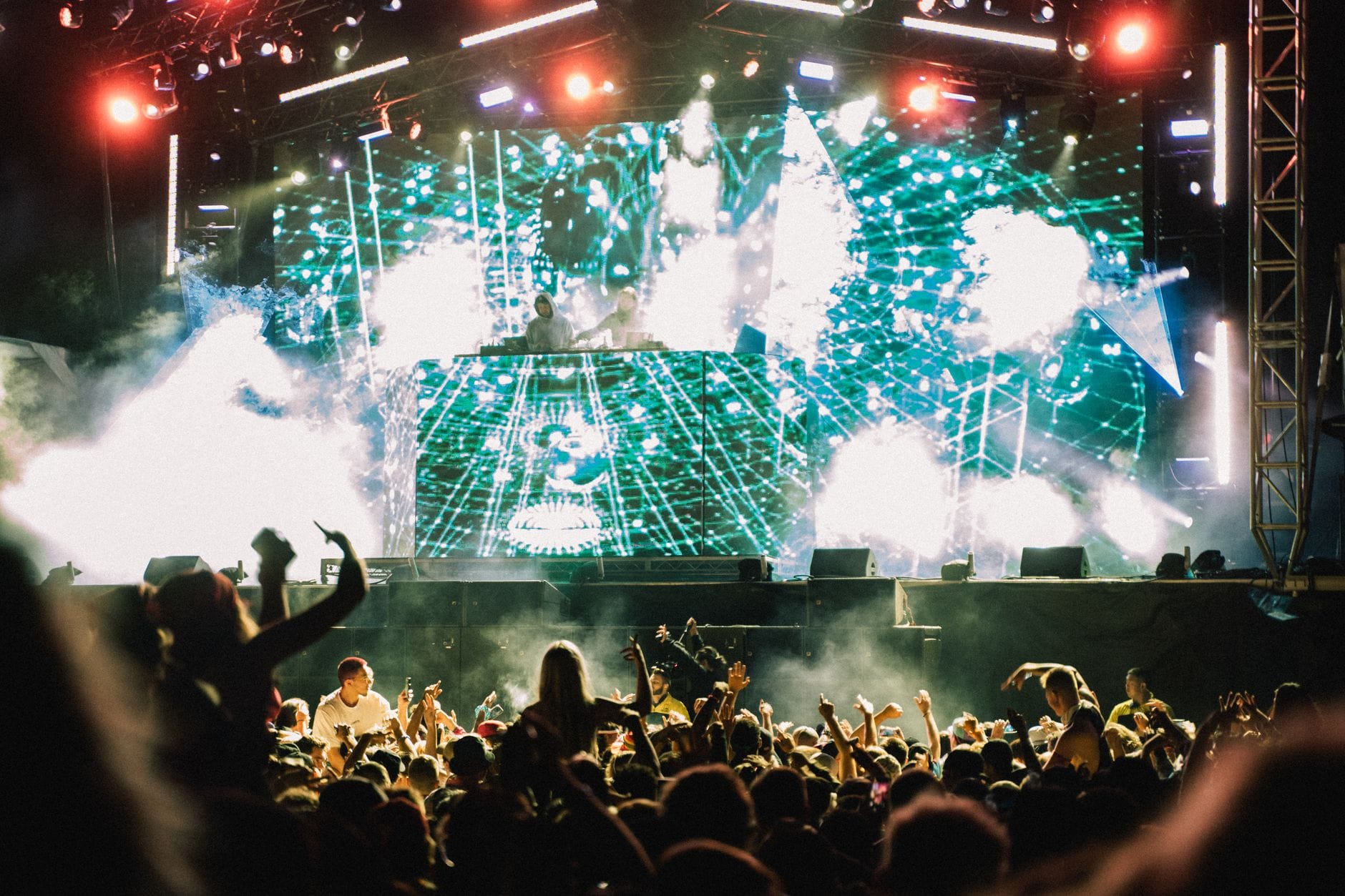 DJ na nocnym festiwalu muzycznym i tłum w blasku świateł