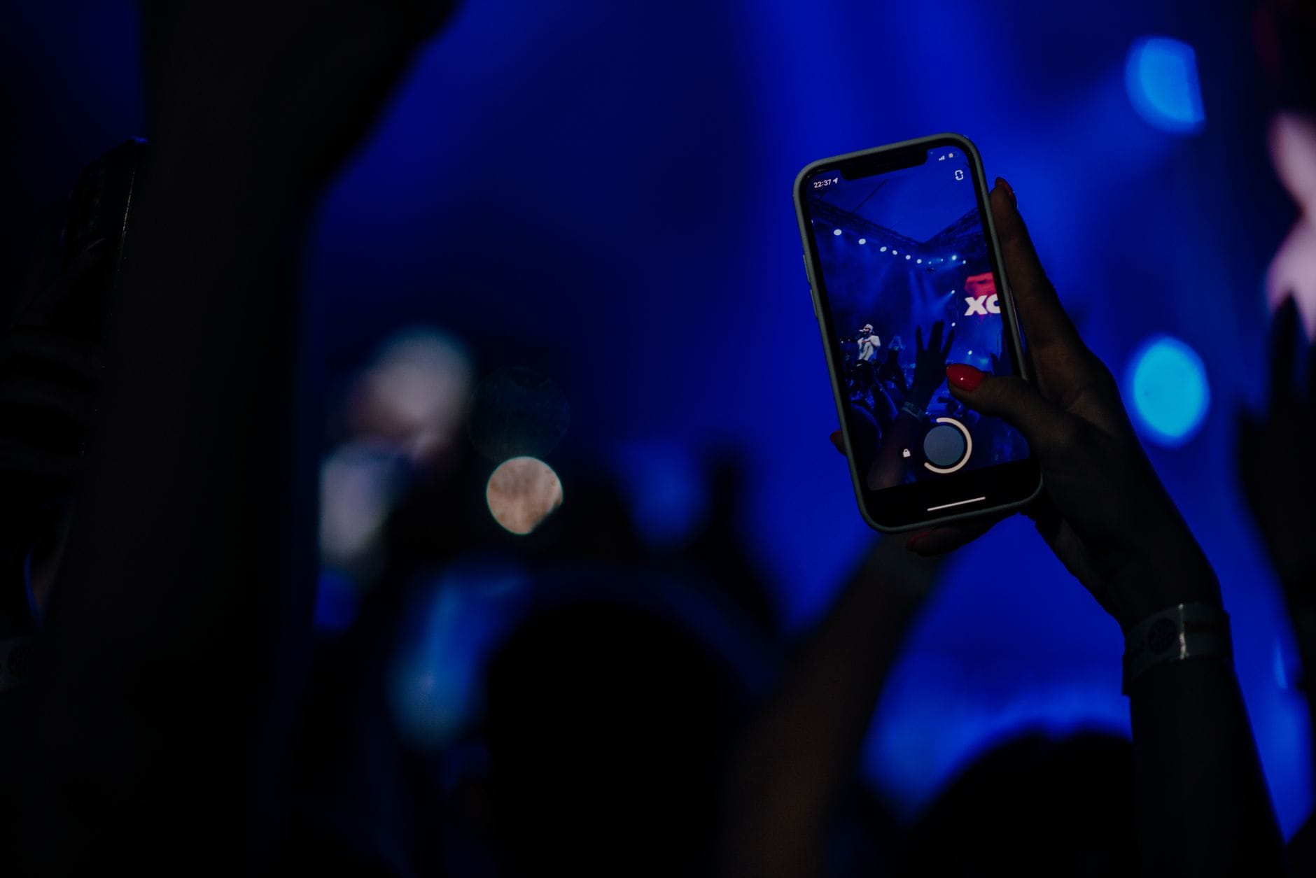Fani nagrywają koncert smartfonami w kolorowym klubie nocnym