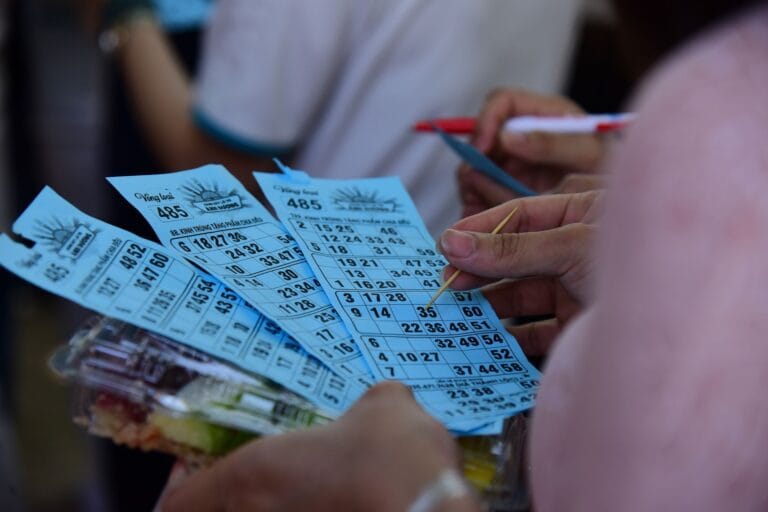 Uczestnicy eventu grają w bingo, trzymając niebieskie